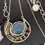 Faceted labradorite oval gemstones within a sterling silver pendant filled with pyrite gemstones and blue purple crystals and brass twist wire
