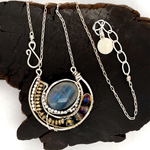 Faceted labradorite oval gemstones within a sterling silver pendant filled with pyrite gemstones and blue purple crystals and brass twist wire