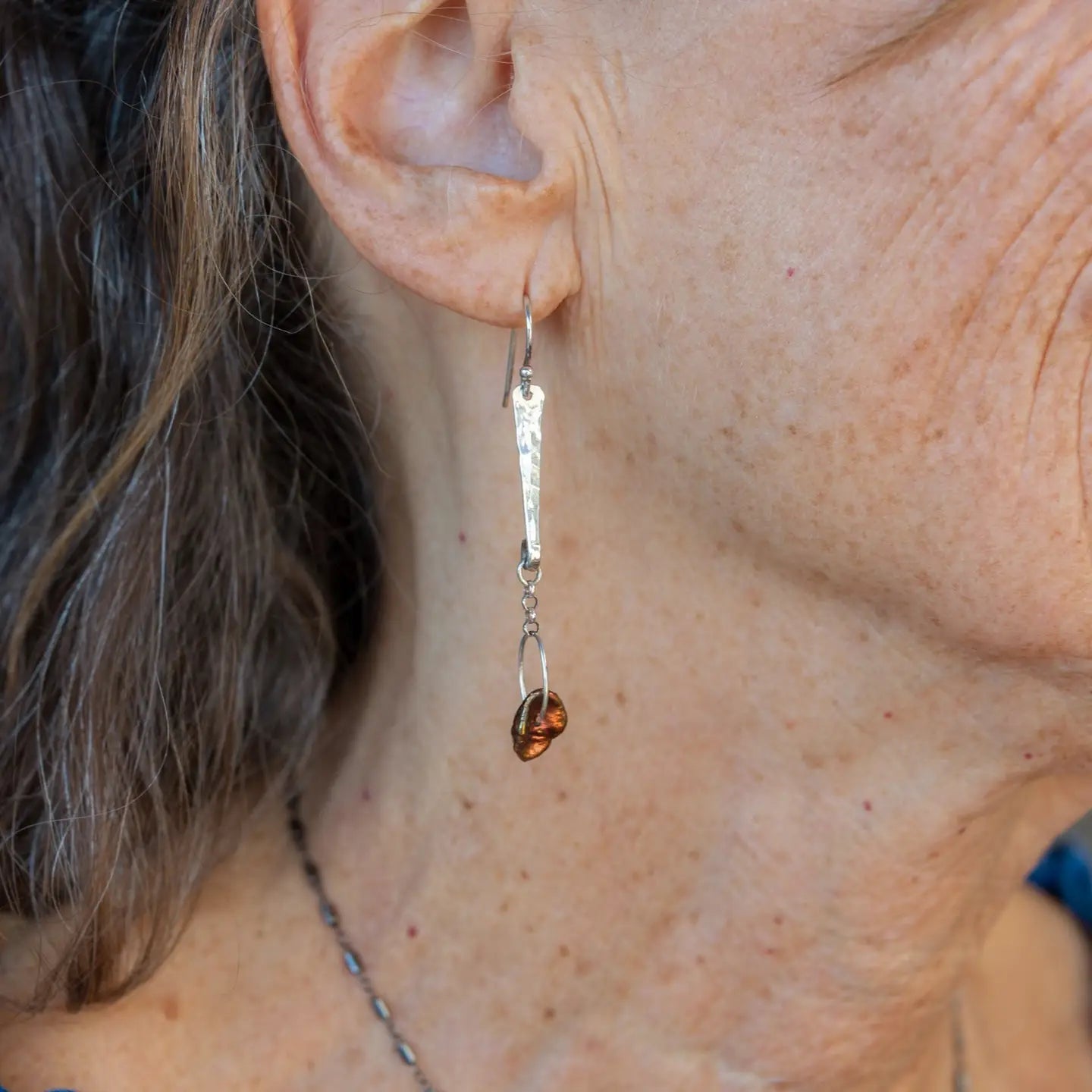 Handmade hammered sterling silver bar earrings with a rust orange colored fresh water pearl dangle