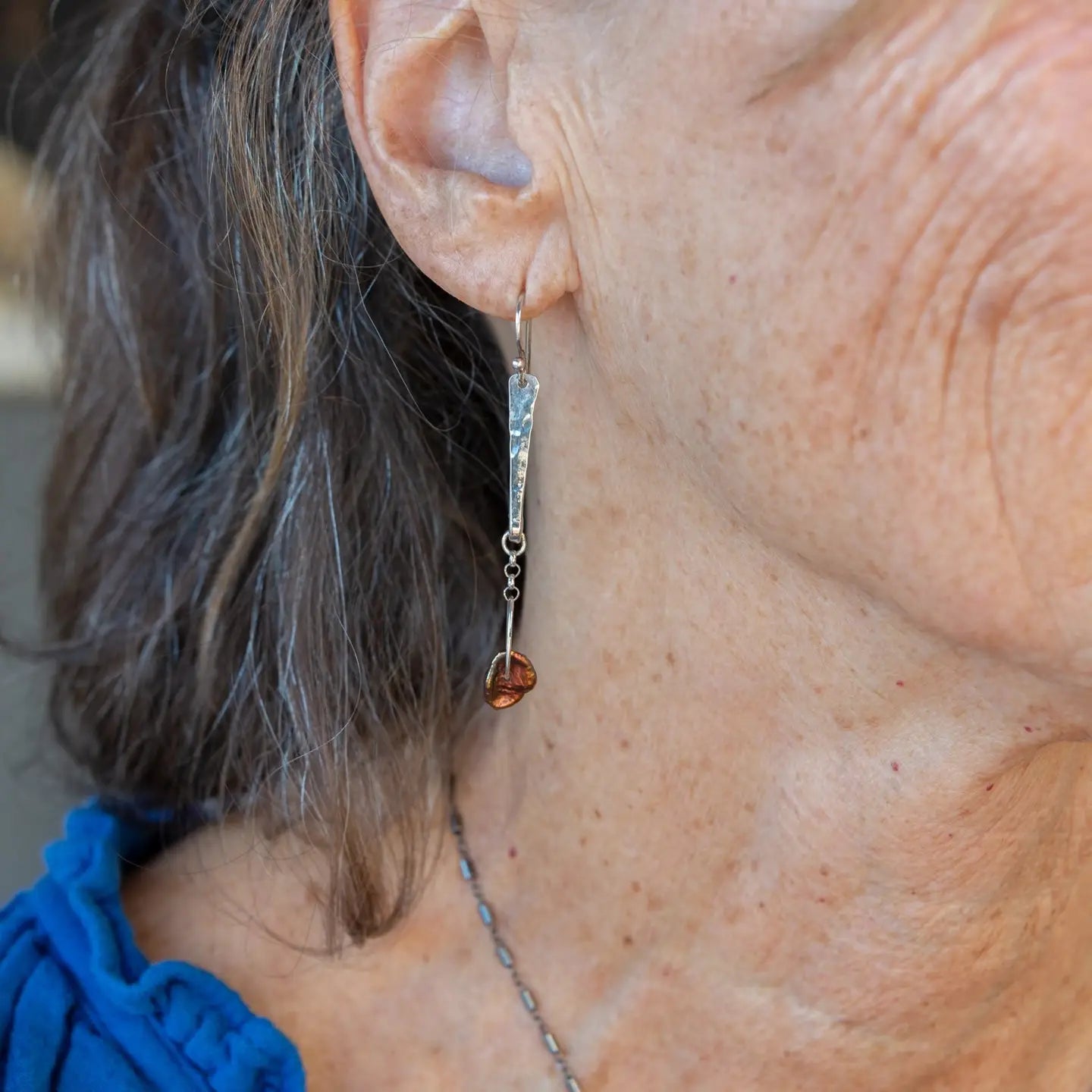 Handmade hammered sterling silver bar earrings with a rust orange colored fresh water pearl dangle