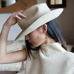 A pair of gold-filled hammered hoop earrings with pastel freshwater pearls set into them.