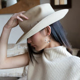 A pair of gold-filled hammered hoop earrings with pastel freshwater pearls set into them.