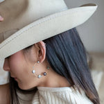 A pair of gold-filled hammered hoop earrings with pastel freshwater pearls set into them.