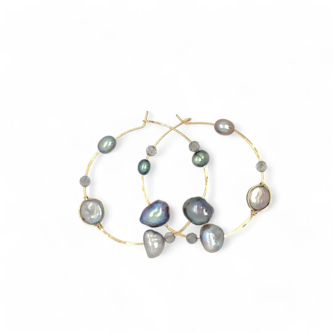 A pair of gold-filled hammered hoop earrings with pastel freshwater pearls set into them.