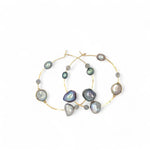 A pair of gold-filled hammered hoop earrings with pastel freshwater pearls set into them.