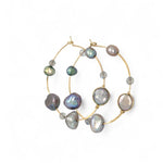 A pair of gold-filled hammered hoop earrings with pastel freshwater pearls set into them.