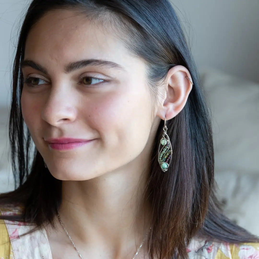 A pair of sterling silver sprout marquise earrings featuring glowing green fire agate, faceted pink garnet, and green kyanite gemstones, with braided oxidized sterling silver veins and silver French hooks.