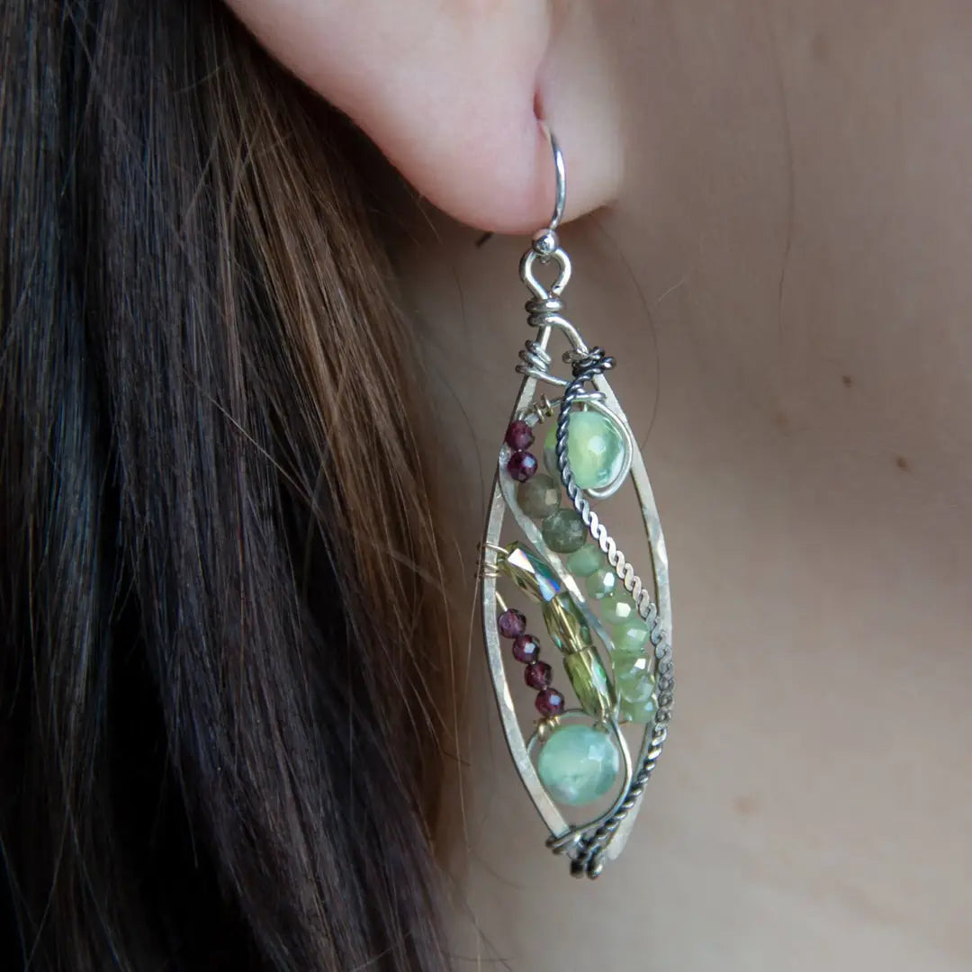 A pair of sterling silver sprout marquise earrings featuring glowing green fire agate, faceted pink garnet, and green kyanite gemstones, with braided oxidized sterling silver veins and silver French hooks.