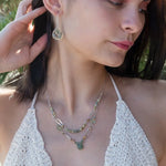 A pair of sterling silver drop earrings with faceted green kyanite gemstones and green amethyst coins, held on bar chain stems.