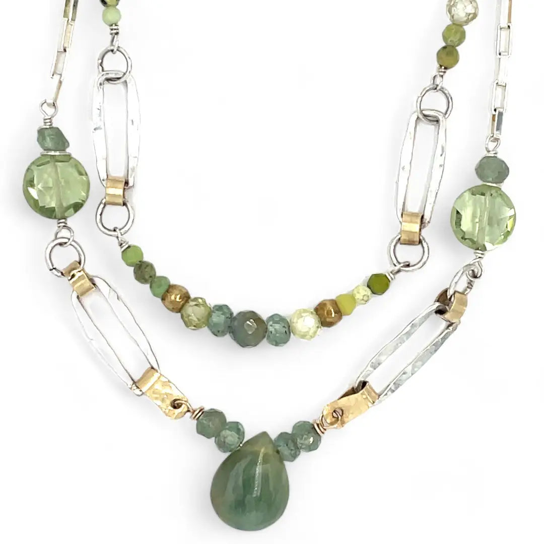 A double chain necklace with handmade hammered sterling silver rectangles and brass rings and straps, with green amethyst, green kyanite, crystal, cubic zirconia, and african metal beads