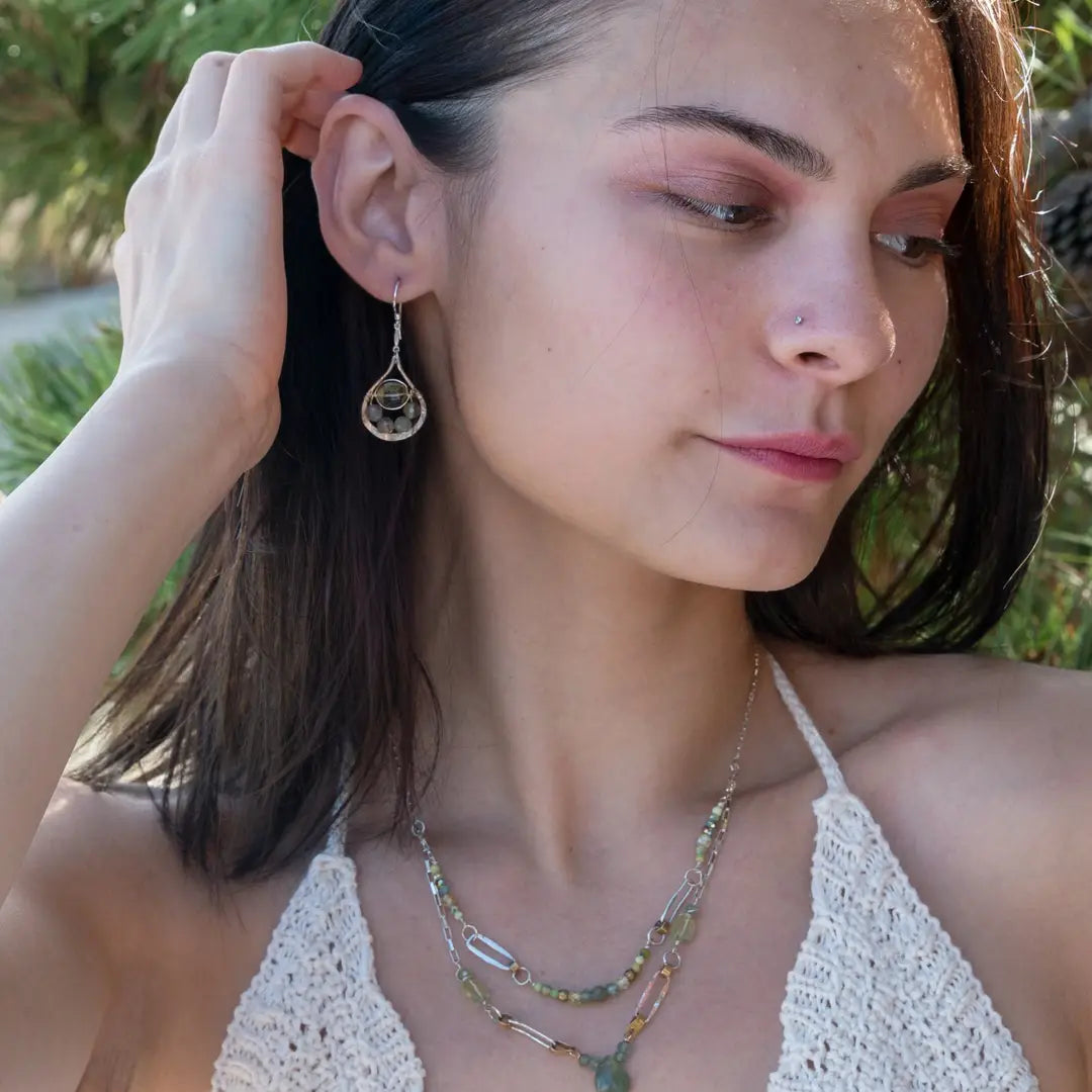 A double chain necklace with handmade hammered sterling silver rectangles and brass rings and straps, with green amethyst, green kyanite, crystal, cubic zirconia, and african metal beads