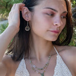 A double chain necklace with handmade hammered sterling silver rectangles and brass rings and straps, with green amethyst, green kyanite, crystal, cubic zirconia, and african metal beads