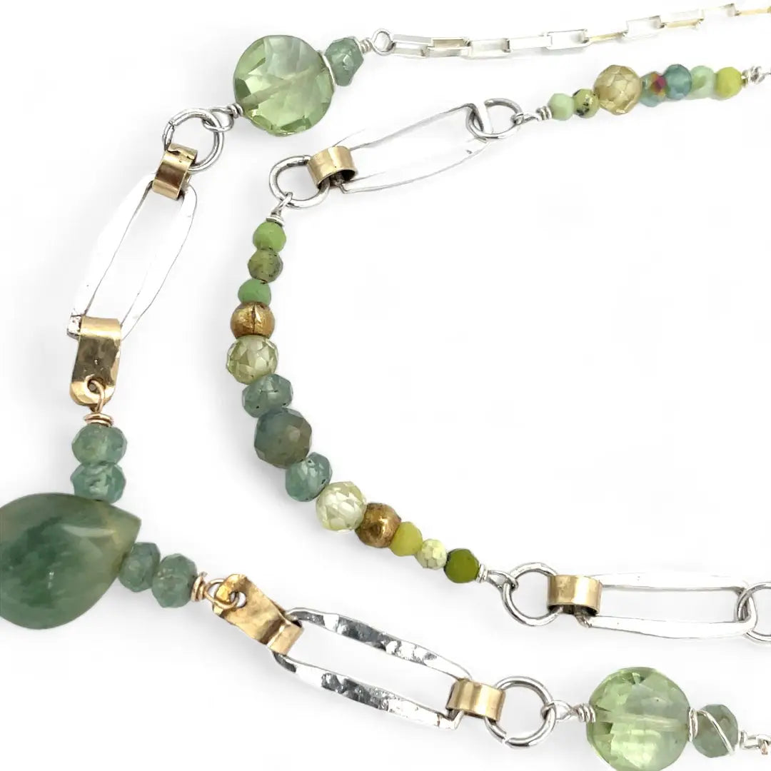 A double chain necklace with handmade hammered sterling silver rectangles and brass rings and straps, with green amethyst, green kyanite, crystal, cubic zirconia, and african metal beads