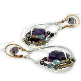 Dark amethyst nuggets are lined with pyrite, crystal, and garnet gemstones in sterling silver wire within sterling silver drops, hanging from bronze channel tops with iolite gemstones