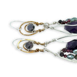 Dark amethyst nuggets are lined with pyrite, crystal, and garnet gemstones in sterling silver wire within sterling silver drops, hanging from bronze channel tops with iolite gemstones