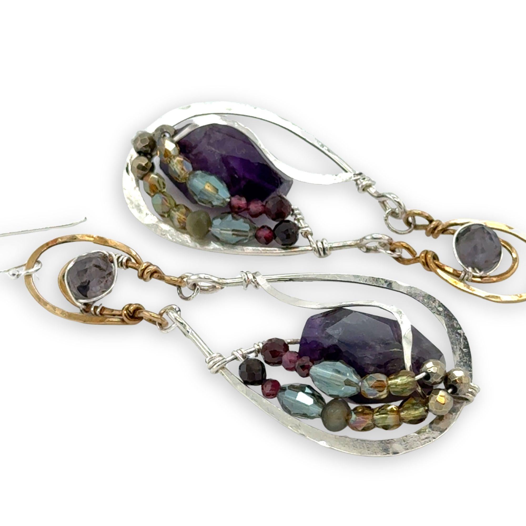 Dark amethyst nuggets are lined with pyrite, crystal, and garnet gemstones in sterling silver wire within sterling silver drops, hanging from bronze channel tops with iolite gemstones