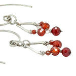 Tiny hammered sterling silver teardrops with red cubic zirconia hang from our handmade sterling silver hoop earrings