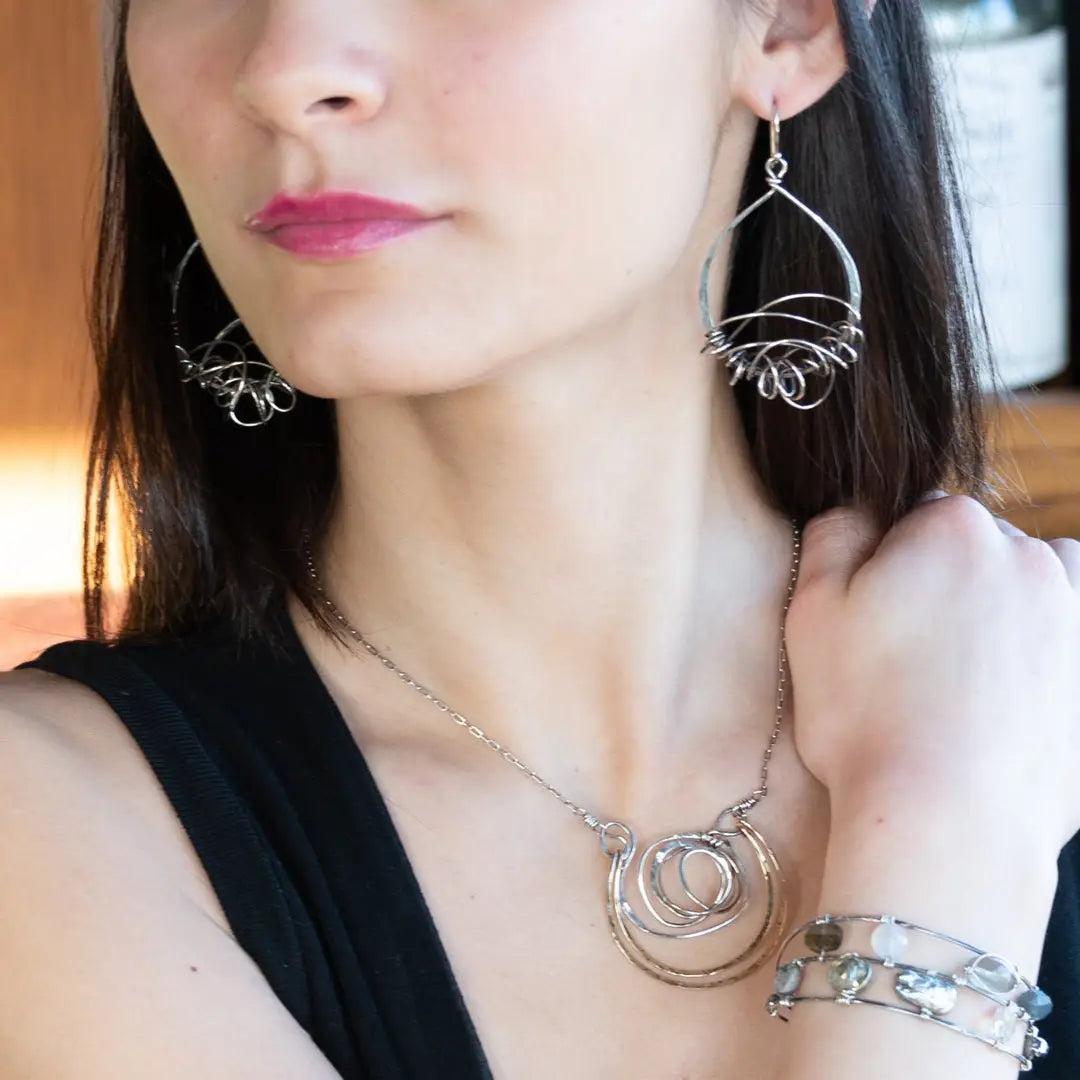 Darkened sterling silver drop earrings with gestural knots at the bottom of the earrings