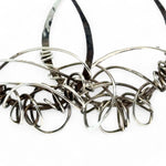 Darkened sterling silver drop earrings with gestural knots at the bottom of the earrings