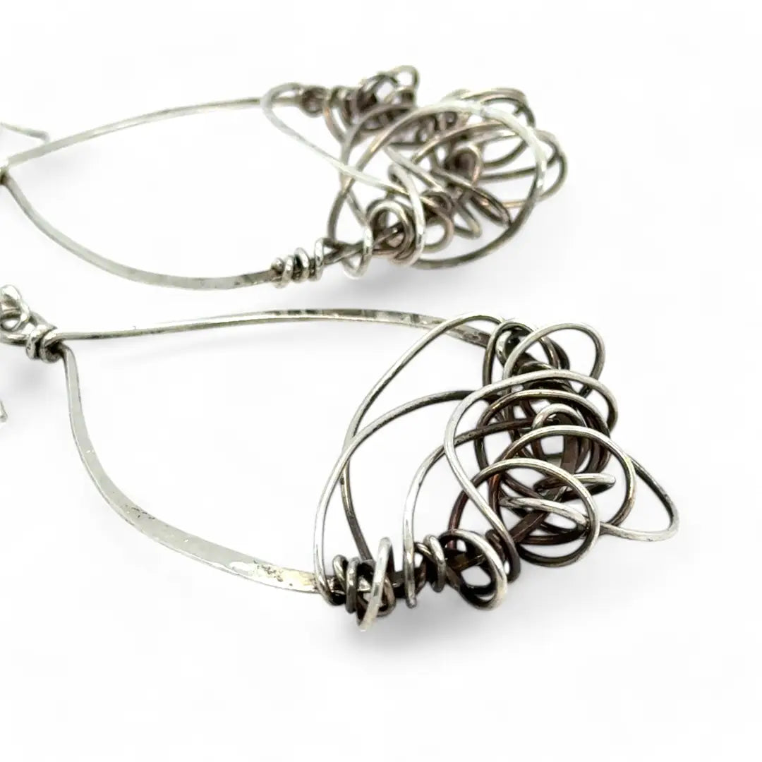 Darkened sterling silver drop earrings with gestural knots at the bottom of the earrings