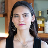 Darkened sterling silver drop earrings with gestural knots at the bottom of the earrings