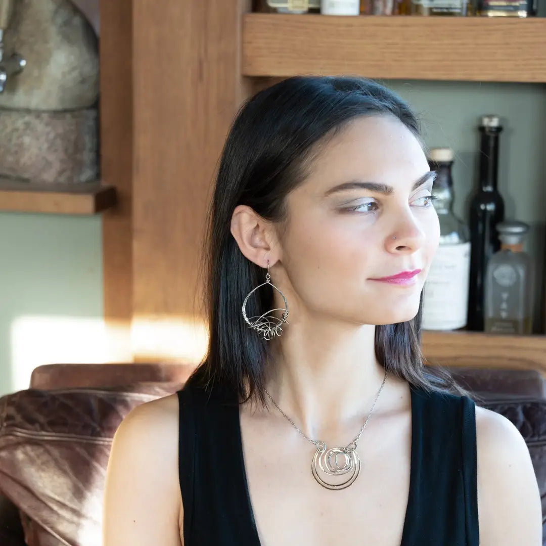 Darkened sterling silver drop earrings with gestural knots at the bottom of the earrings