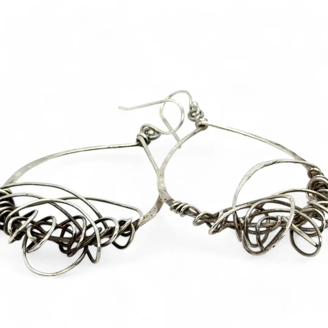 Darkened sterling silver drop earrings with gestural knots at the bottom of the earrings
