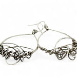 Darkened sterling silver drop earrings with gestural knots at the bottom of the earrings