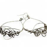 Darkened sterling silver drop earrings with gestural knots at the bottom of the earrings