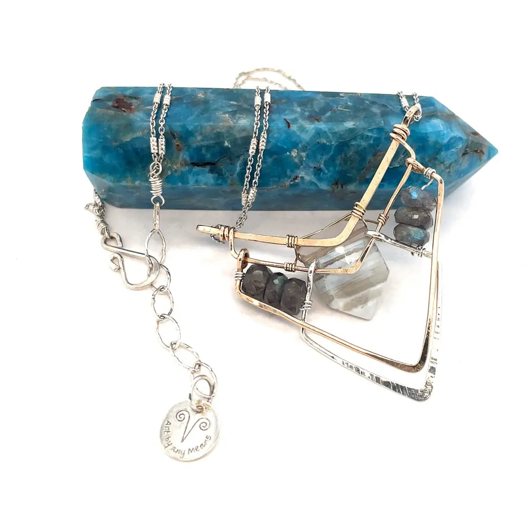 A brass and sterling silver pendant necklace featuring a blue lace agate point and faceted flashy labradorite gemstones with a doubled sterling silver sparkly chain
