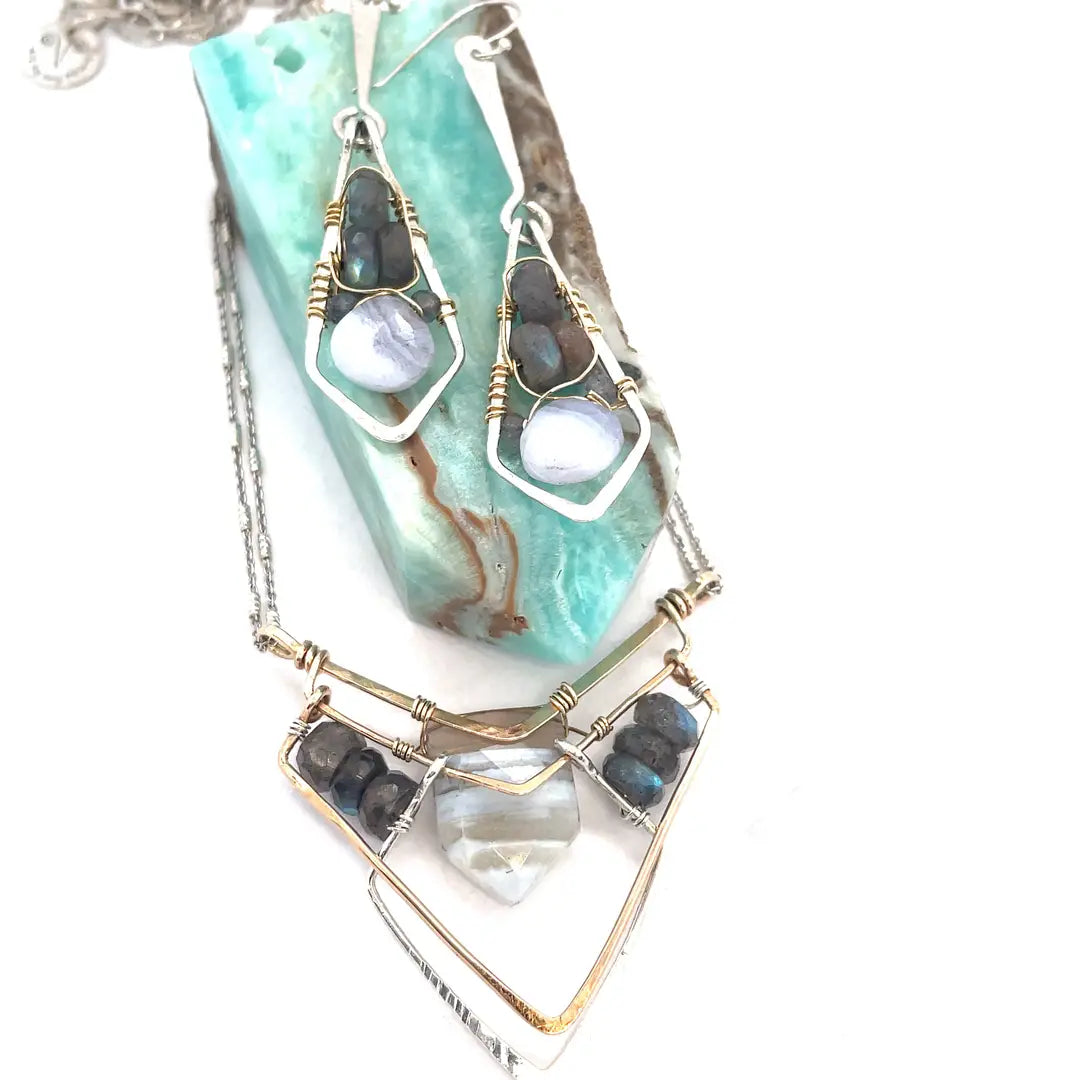 A brass and sterling silver pendant necklace featuring a blue lace agate point and faceted flashy labradorite gemstones with a doubled sterling silver sparkly chain