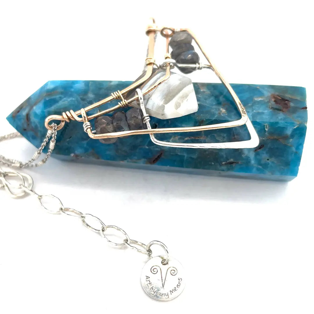 A brass and sterling silver pendant necklace featuring a blue lace agate point and faceted flashy labradorite gemstones with a doubled sterling silver sparkly chain