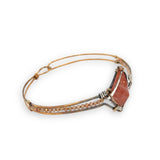 Bronze cuff bracelet with a darkened center carrying a stud cut sunstone diamond surrounded by sterling silver hammered wire and gold filled wire, accented by peach sparkly cubic zirconia