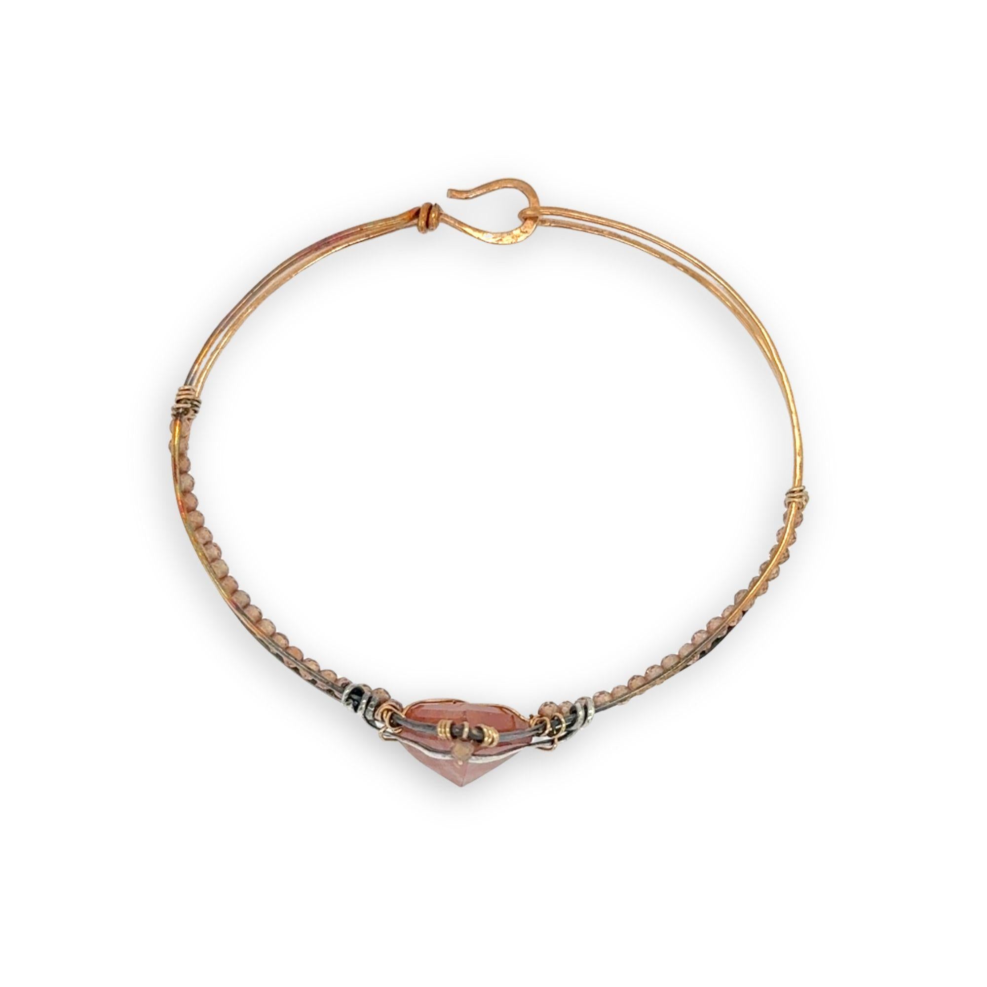 Bronze cuff bracelet with a darkened center carrying a stud cut sunstone diamond surrounded by sterling silver hammered wire and gold filled wire, accented by peach sparkly cubic zirconia