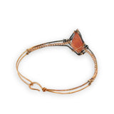 Bronze cuff bracelet with a darkened center carrying a stud cut sunstone diamond surrounded by sterling silver hammered wire and gold filled wire, accented by peach sparkly cubic zirconia