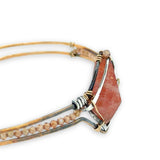 Bronze cuff bracelet with a darkened center carrying a stud cut sunstone diamond surrounded by sterling silver hammered wire and gold filled wire, accented by peach sparkly cubic zirconia