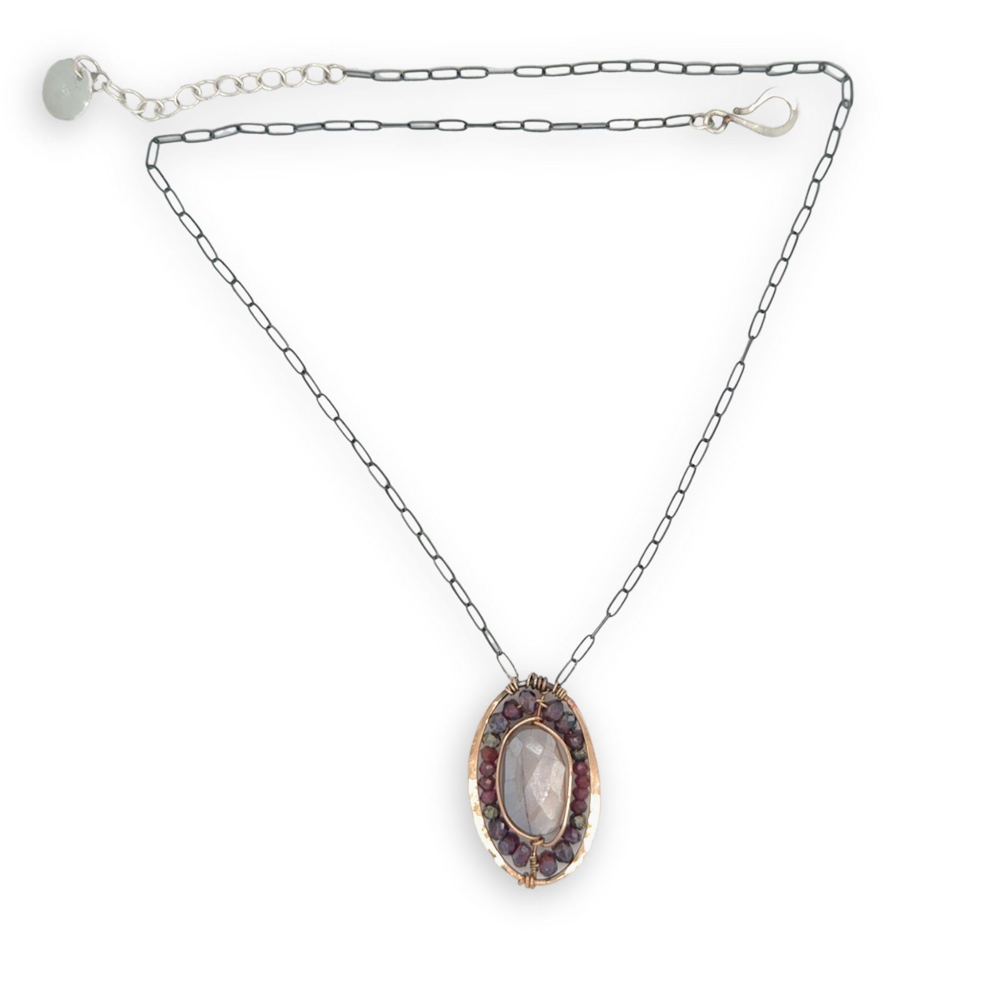 Bronze oval pendant filled with mauve moonstone, garnet, and pyrite gemstones with a darkened sterling silver oval chain necklace