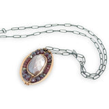 Bronze oval pendant filled with mauve moonstone, garnet, and pyrite gemstones with a darkened sterling silver oval chain necklace