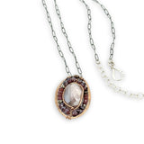 Bronze oval pendant filled with mauve moonstone, garnet, and pyrite gemstones with a darkened sterling silver oval chain necklace