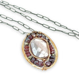 Bronze oval pendant filled with mauve moonstone, garnet, and pyrite gemstones with a darkened sterling silver oval chain necklace