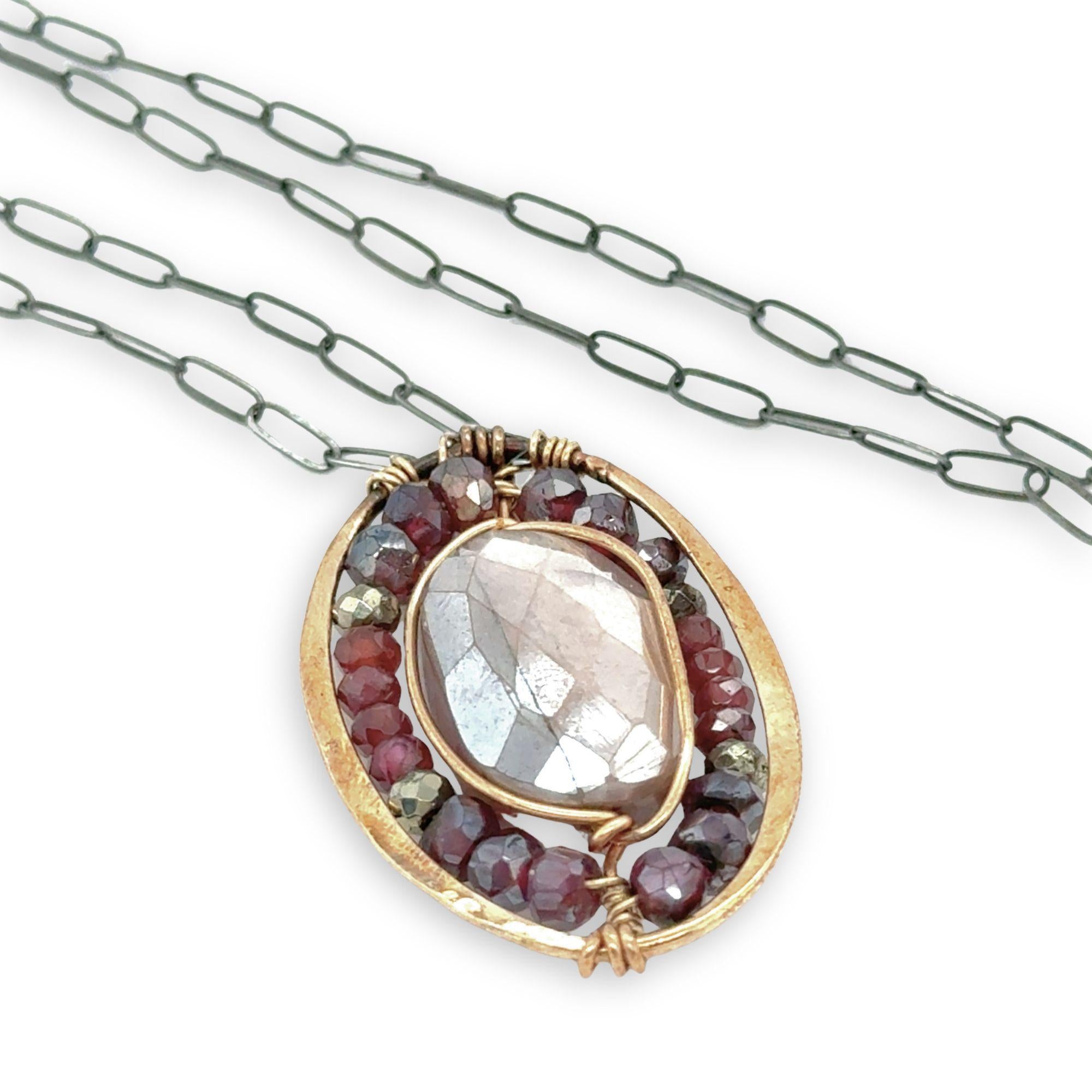 Bronze oval pendant filled with mauve moonstone, garnet, and pyrite gemstones with a darkened sterling silver oval chain necklace