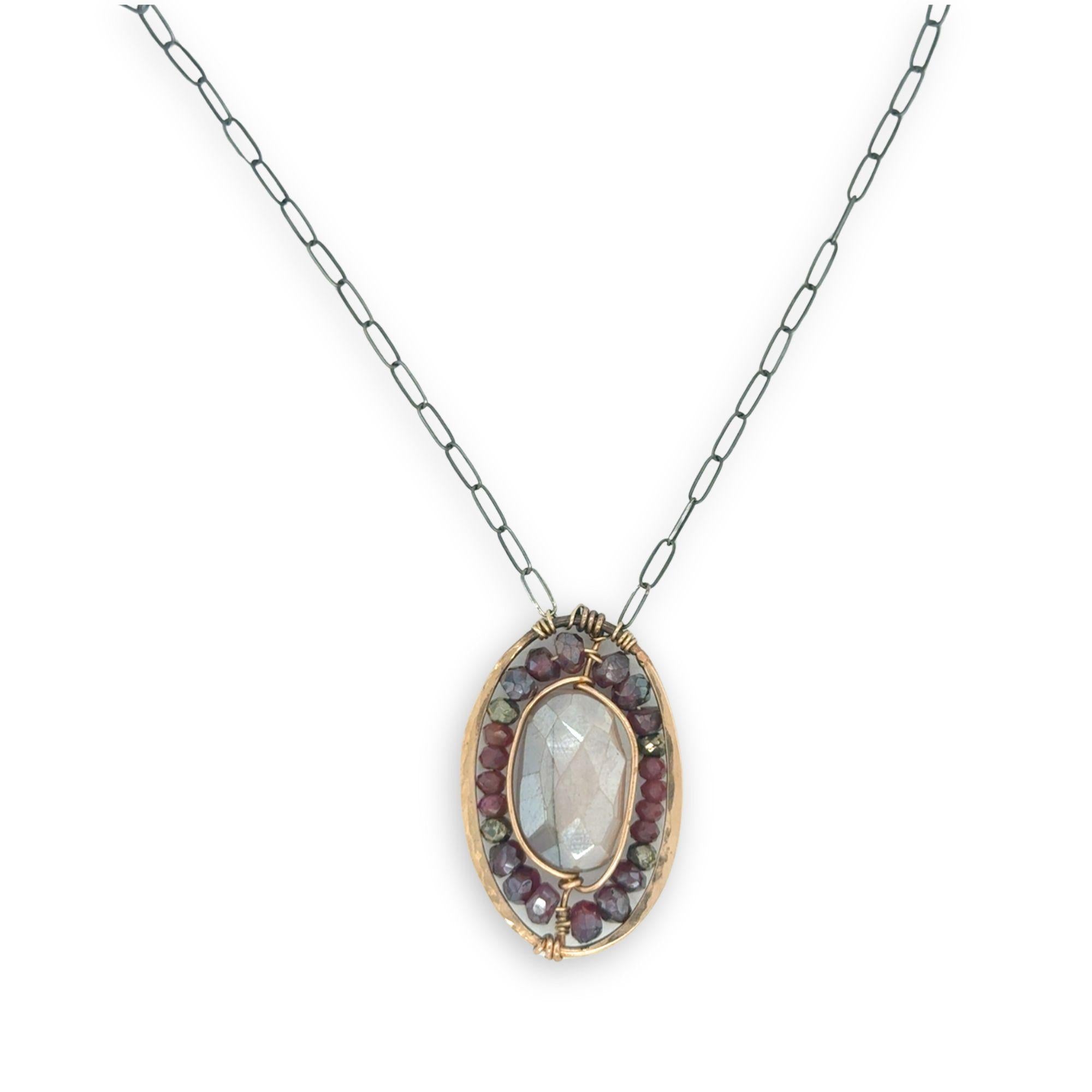 Bronze oval pendant filled with mauve moonstone, garnet, and pyrite gemstones with a darkened sterling silver oval chain necklace