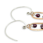 mini bronze teardrops filled with garnet and pyrite gemstones hanging from our handmade sterling silver hoop earrings
