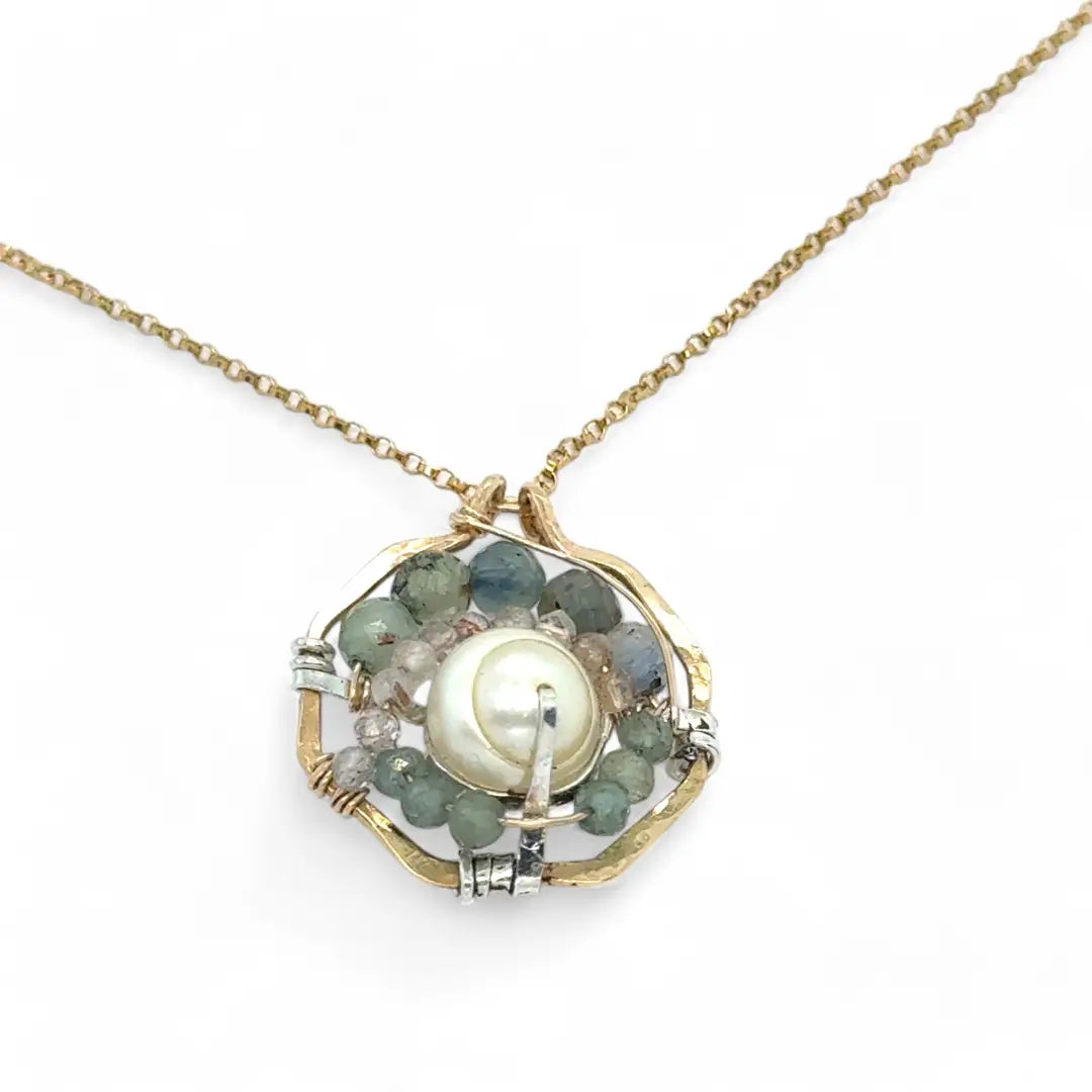 A brass hammered hexagon pendant necklace with a central pearl surrounded by a spiral of rutilated quartz and green kyanite gemstones, on a gold-filled rolo chain 