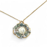 A brass hammered hexagon pendant necklace with a central pearl surrounded by a spiral of rutilated quartz and green kyanite gemstones, on a gold-filled rolo chain 