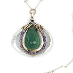 A necklace featuring a hand made thistle-shaped pendant with a green amethyst faceted drop gemstone and micro faceted lavender cubic zirconia gemstones, on a sterling silver bar chain.