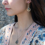 Sterling silver leaf stamped drop earrings with green kyanite gemstones and purple crystal drops wrapped in hammered brass wire, on sterling silver bar chain