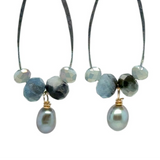 A pair of handmade sterling silver drop earrings with aquamarine faceted gemstones, crystals, and silvery freshwater pearls dangle from gold-filled accents.