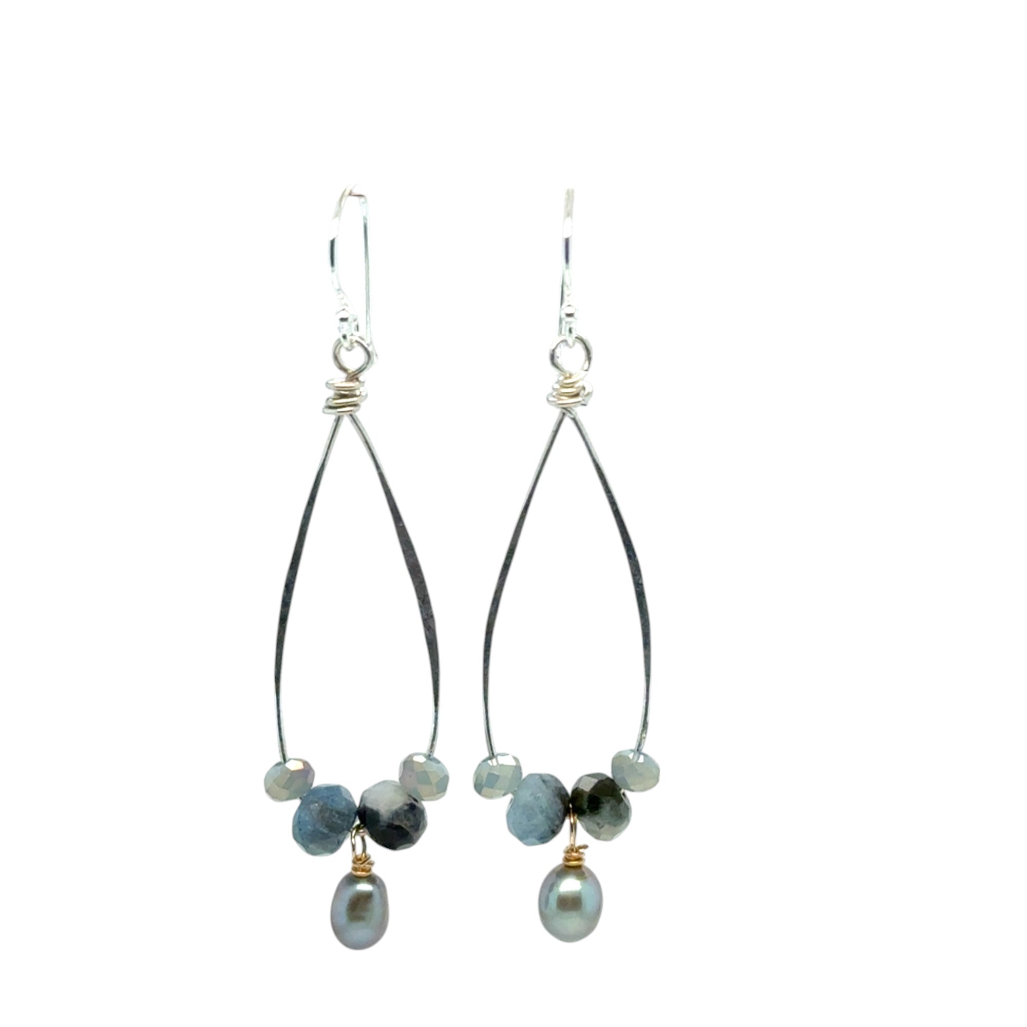A pair of handmade sterling silver drop earrings with aquamarine faceted gemstones, crystals, and silvery freshwater pearls dangle from gold-filled accents.