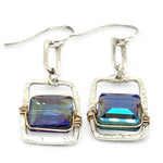 A pair of sterling silver box earrings with ocean blue crystal tiles wrapped in gold filled wire, hanging from a textured sterling silver link